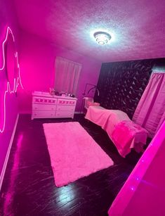 a bedroom with pink walls and black flooring is lit up by neon colored lights