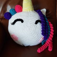 a crocheted unicorn pillow sitting on top of a brown chair