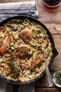 a skillet filled with pasta and meatballs on top of a wooden table next to a glass of wine