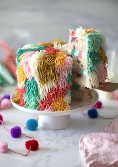 a cake that has been decorated with multicolored icing and pom - poms