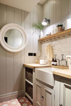 a white sink sitting under a round mirror in a bathroom next to a wooden counter top