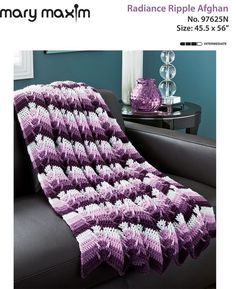 a purple crocheted blanket sitting on top of a couch next to a table