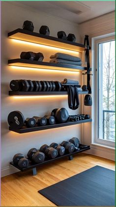 there is a gym room with many dumbs on the wall and exercise mats in front of the window