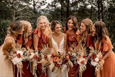 a group of women standing next to each other wearing dresses and holding bouquets in their hands