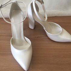 a pair of white high heeled shoes sitting on top of a wooden floor