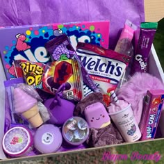 a purple box filled with lots of toys and candy on top of a grass covered field