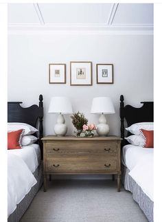 two beds in a room with white walls and pictures on the wall above them,