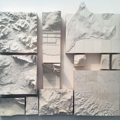 an abstract white sculpture with mountains and valleys in the center, surrounded by smaller pieces of paper