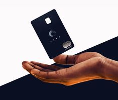 a hand holding a black credit card in front of a white and black background with the moon on it