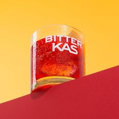 a beer glass sitting on top of a red and yellow table next to an orange wall