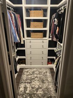 a walk in closet with white shelves, drawers and rug on the carpeted floor