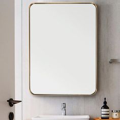 a white sink sitting under a large mirror next to a wall mounted faucet