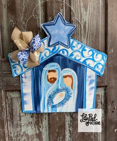 a nativity scene hanging on a wooden door with a star above it and two baby jesus in the manger