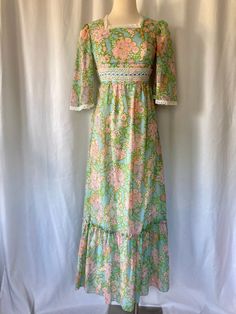 Sweet summery floral Maxi vintage 1970's 1980's Prairie blue with green, pink and purple flowers with green edges, tie back waist and lace trim, angel sleeves with ruffled bottom with back zipper.  Union Made in U.S.A Great vintage condition with no stains or rips  No tag size but best estimated size is XS/Small (4) Measurements (laying flat): Pit to Pit: 16" Waist: 13" Back Length: 55" Our items are vintage, older and/or pre-loved and may show signs of age. Items may have some imperfections, in Vintage Green Spring Maxi Dress, 1970s Style Blue Floral Print Dresses, 1970s Style Floral Print Dress For Garden Party, 1970s Retro Print Spring Dress, Spring Vintage Green Maxi Dress, Vintage Green Maxi Dress For Spring, Vintage Blue Maxi Dress For Spring, Fitted Vintage Print Maxi Dress For Spring, Blue Vintage Maxi Dress For Spring