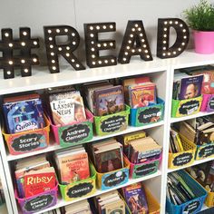 a book shelf filled with lots of children's books next to a sign that says read