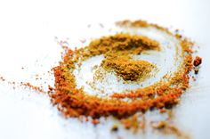 a pile of ground spices sitting on top of a white tablecloth covered in orange and yellow powder