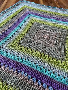 a multicolored crocheted blanket on a wooden floor