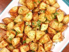 cooked potatoes with parsley in a white dish on a wooden table top, ready to be eaten