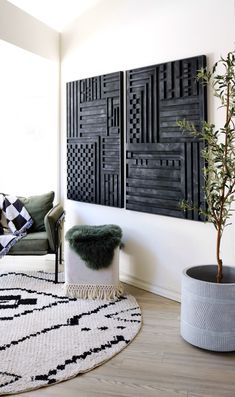 a living room with two black and white panels on the wall, a small tree in a potted plant next to it