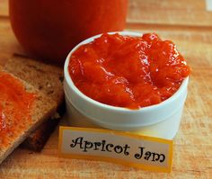 a bowl of apricot jam next to a slice of bread