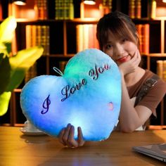 a woman sitting at a table with a heart shaped pillow that says i love you