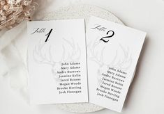 two place cards with antlers on them sitting next to a bouquet of dried flowers