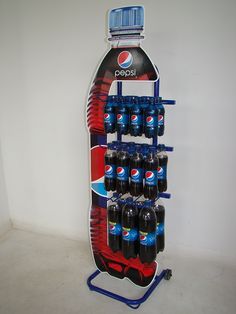 a display case with soda and pepsi bottles on it's sides, in front of a white wall