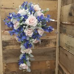 a bouquet of blue and pink flowers on top of a wooden wall in front of a door