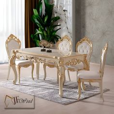 a dining room table with white chairs and a plant in the corner next to it