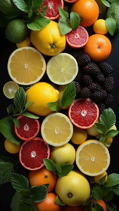 an arrangement of citrus fruits with leaves, berries and lemons on a black background