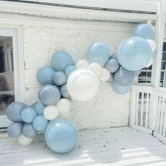 blue and white balloons are hanging from the side of a house's front door