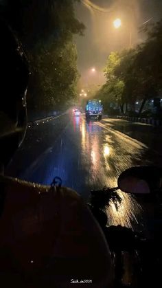 a car driving down the road at night with its headlights on and it's raining