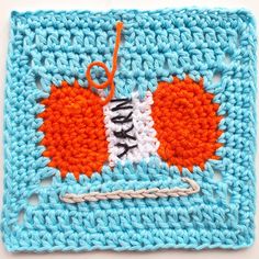 an orange and white crochet square with two hearts on it