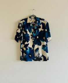 Blue Hawaiian! Brilliant vintage Hawaiian shirt in a bold yet somehow  calming bold blue tropical flower print.  Front pocket, four buttons up the front. And I'm not positive, but I think it's King K'meah Meah on the buttons.  Hawaiian Casuals By Stan Hicks, Made in Honolulu  Size XL (?) Measures: 23" from armpit to armpit 6.5" from collar to shoulder seam 6"" from armpit to end of sleeve 29" from shoulder to bottom hem (down the front) Vintage Hawaiian Shirts, Blue Hawaiian, Tropical Flower, Vintage Hawaiian, Mens Oxfords, Mens Shirt, Honolulu, Tucson, Flower Print