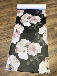 a black and white floral print yoga mat with rolled up paper on the floor next to it