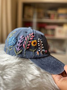 a hat with embroidered flowers on it sitting on top of a white furnishing