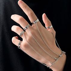 a person wearing four different rings and chains on their hands with one hand in the air