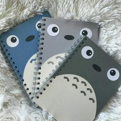 two notebooks with different designs on them sitting on a white blanket, one has an animal face and the other is a giraffe's nose