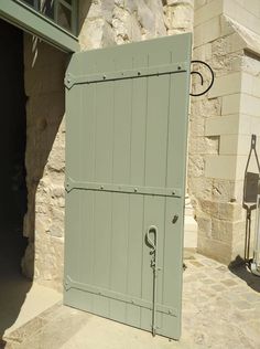 an open green door in front of a stone building