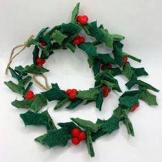 a christmas wreath made out of felt with red berries and green leaves