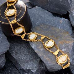 This elegant bracelet features seven oval shell cameos bezel-set along chain and teardrop shaped gold tablets to create an undulating effect. The bracelet has French hallmarks on the slide-in clasp. The bracelet is crafted in 18k yellow gold and fits up to a 7 inch wrist. Elegant Gold Bracelet With Cabochon, Elegant Gold Bracelets With Cabochon, Elegant Formal Cabochon Bracelets, Gold Cabochon Bracelets For Formal Occasions, Victorian Gold Bracelets With Cabochon, Elegant Gold Cameo Bracelets, Elegant Gold Bracelet With Oval Cabochon, Elegant Gold Oval Cabochon Bracelet, Elegant Cameo Bracelet For Formal Occasions