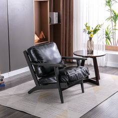 a black leather chair sitting on top of a wooden floor next to a glass table