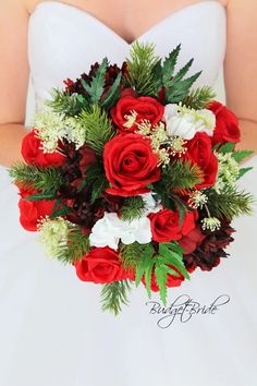 a bride holding a bouquet of red roses and greenery on her wedding day,