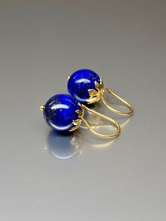 Beautiful vibrant and high-grade lapis lazuli globe earrings. The 12.5 mm lapis lazuli globes have a gorgeous deep vibrant royal blue color that shows celestial flecks of golden pyrite in the stone. The ultra-fine globes attached to a beautiful 14K gold-filled flower caps as they attached the vermeil on sterling ear wires. These are elegant and perfect earrings to go with any outfit. A pair of fine gemstone essentials. *Ball size (diameter): 12.5 mm *Metal: vermeil on sterling *Earrings drop len Blue Polished Drop Earrings, Blue Drop Earrings With Polished Finish, Round Lapis Lazuli Gemstone Earrings, Elegant Lapis Lazuli Gemstone Earrings, Blue Lapis Lazuli Earrings For Formal Occasions, Pierced Lapis Lazuli Round Jewelry, Blue Lapis Lazuli Earrings, Elegant Lapis Lazuli Earrings For Gift, Elegant Lapis Lazuli Earrings As A Gift