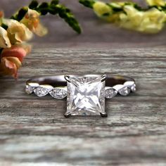 an engagement ring with a princess cut diamond surrounded by pave diamonds on a wooden surface