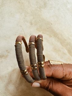 A beautifully handcrafted torque style brass cuff, accented with twisted brass, copper and lightly textured brass beads. Each bracelet is adjustable and can be adjusted to fix smaller or larger wrist. Handmade by African artisans in Kenya. DETAILS: Unisex Metal: Solid Brass & Copper Ships with polishing cloth for everlasting wear. Due to the handmade nature, expect slight imperfections. Each is one of a kind. *Packaged for gift giving. *Sold Individually (1 Bracelet). Not a set. Adjustable Artisan Metal Bangle, Adjustable Brass Beaded Bracelets, Bohemian Antique Gold Adjustable Bracelets, Antique Gold Adjustable Metal Bracelets, Adjustable Wire Wrapped Bronze Cuff Bracelet, Adjustable Bronze Beaded Brass Bracelets, Adjustable Bronze Brass Bangle, Bohemian Metal Braided Bangle Bracelets, Bohemian Metal Braided Bangle Bracelet