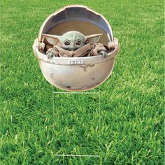 a baby yoda in a metal bowl on green grass with an instagram frame