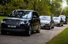 the range rover is lined up on the side of the road with trees in the background