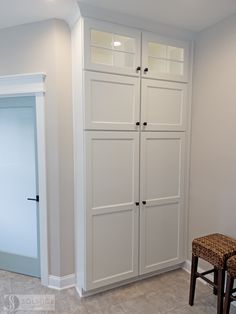 a white closet with two doors and a stool