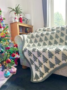 a living room with a christmas tree and a couch covered in a crocheted blanket